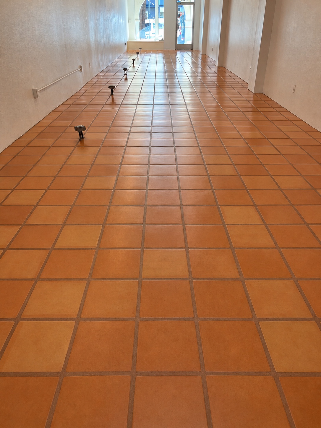 Commercial floor buffers lined up mid-job on freshly cleaned terracotta tile floors