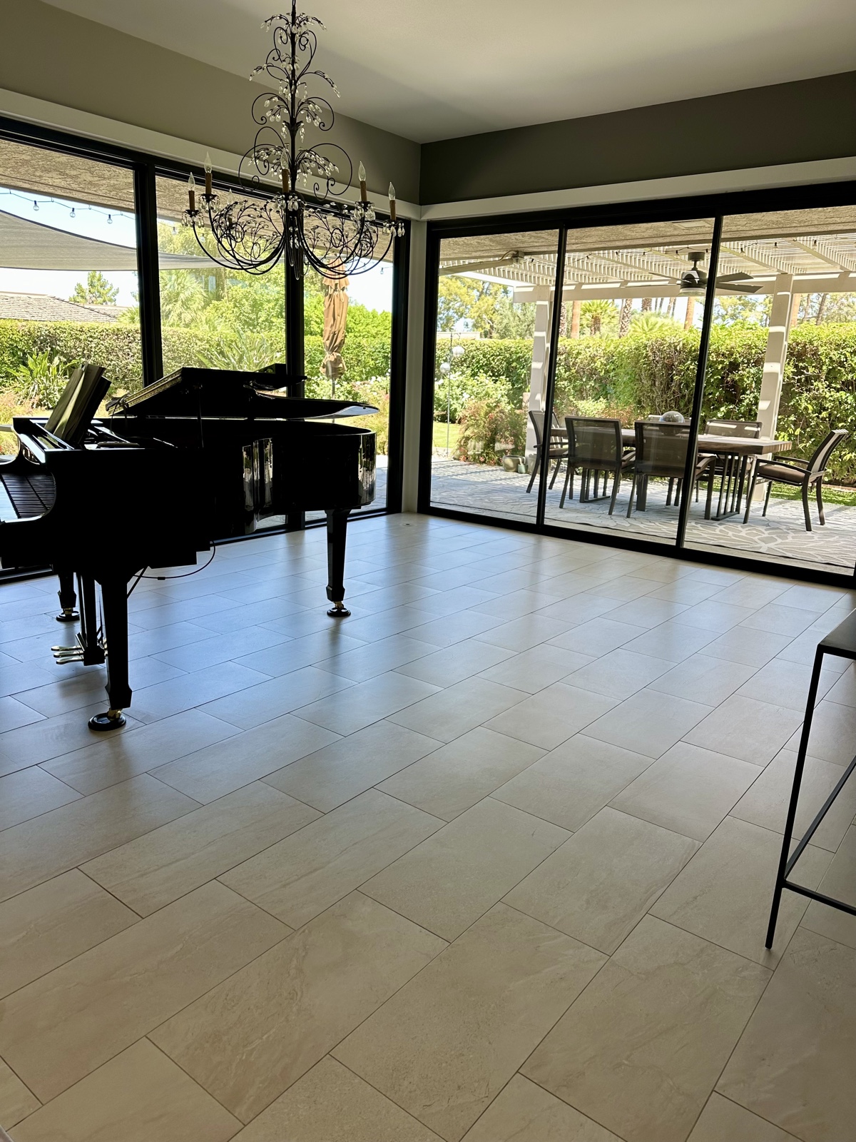 Spotless interior of a high-end Coachella Valley home — gleaming travertine floors, grand piano, and floor-to-ceiling windows opening onto the patio