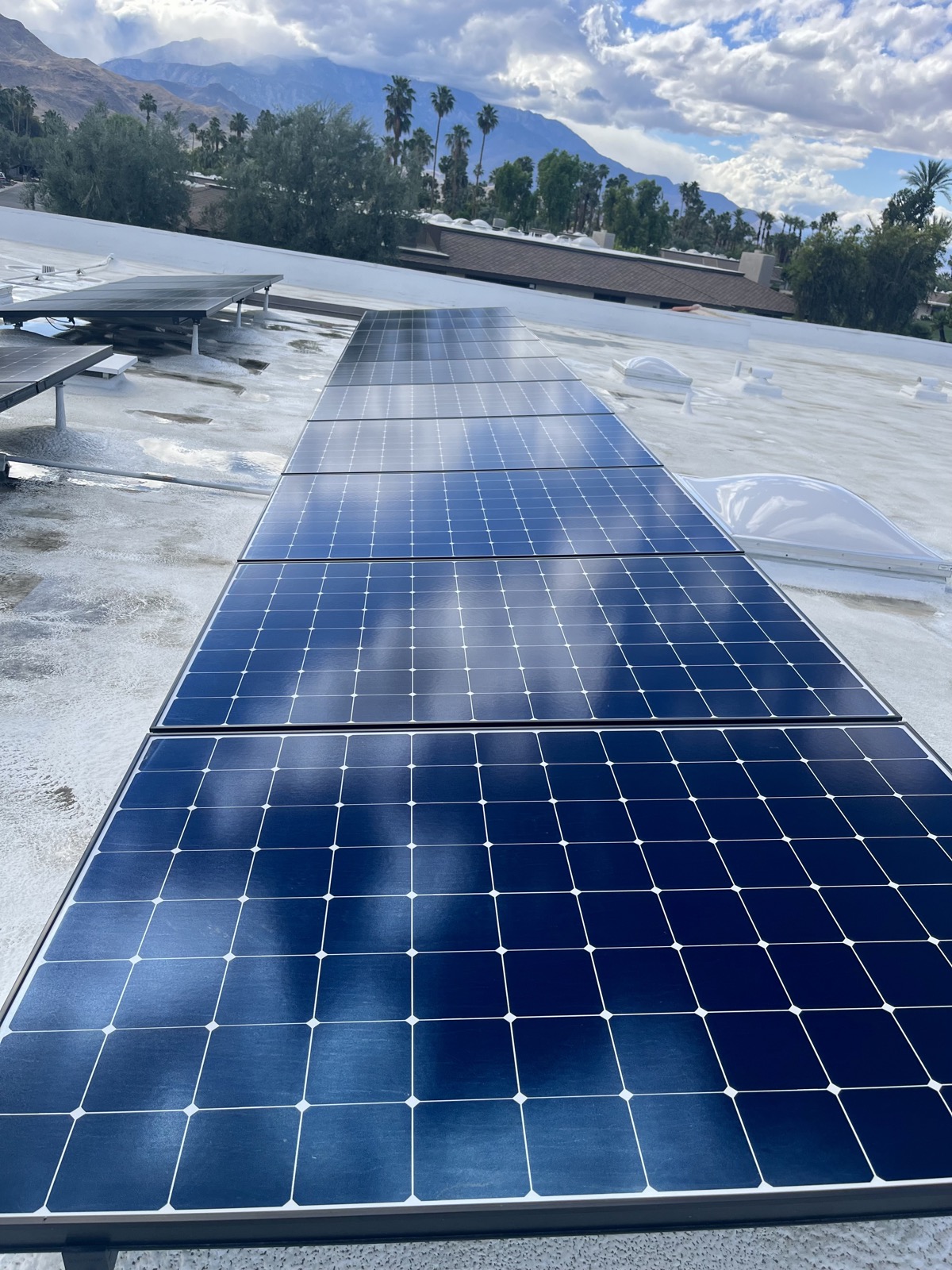 Same solar panels after cleaning — deep blue glossy finish with clouds reflecting cleanly off the surface