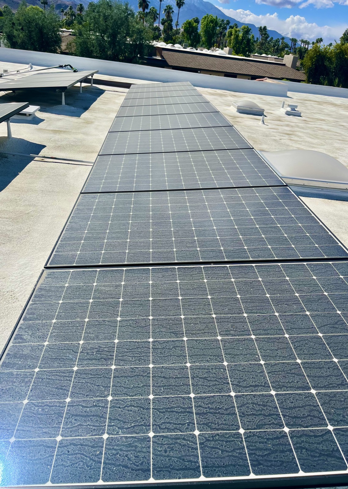 Solar panels before cleaning — desert dust film visible across the panels with Coachella Valley mountains in background