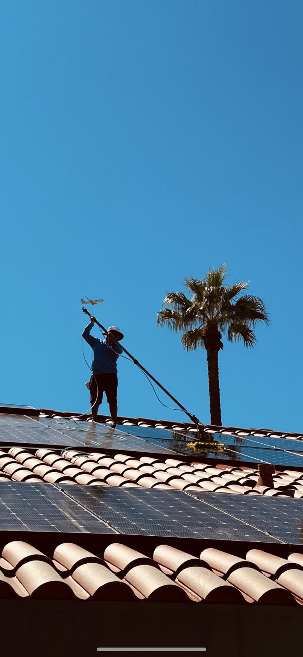 Lalo Rico's crew cleaning solar panels on a tile roof under a clear Coachella Valley sky